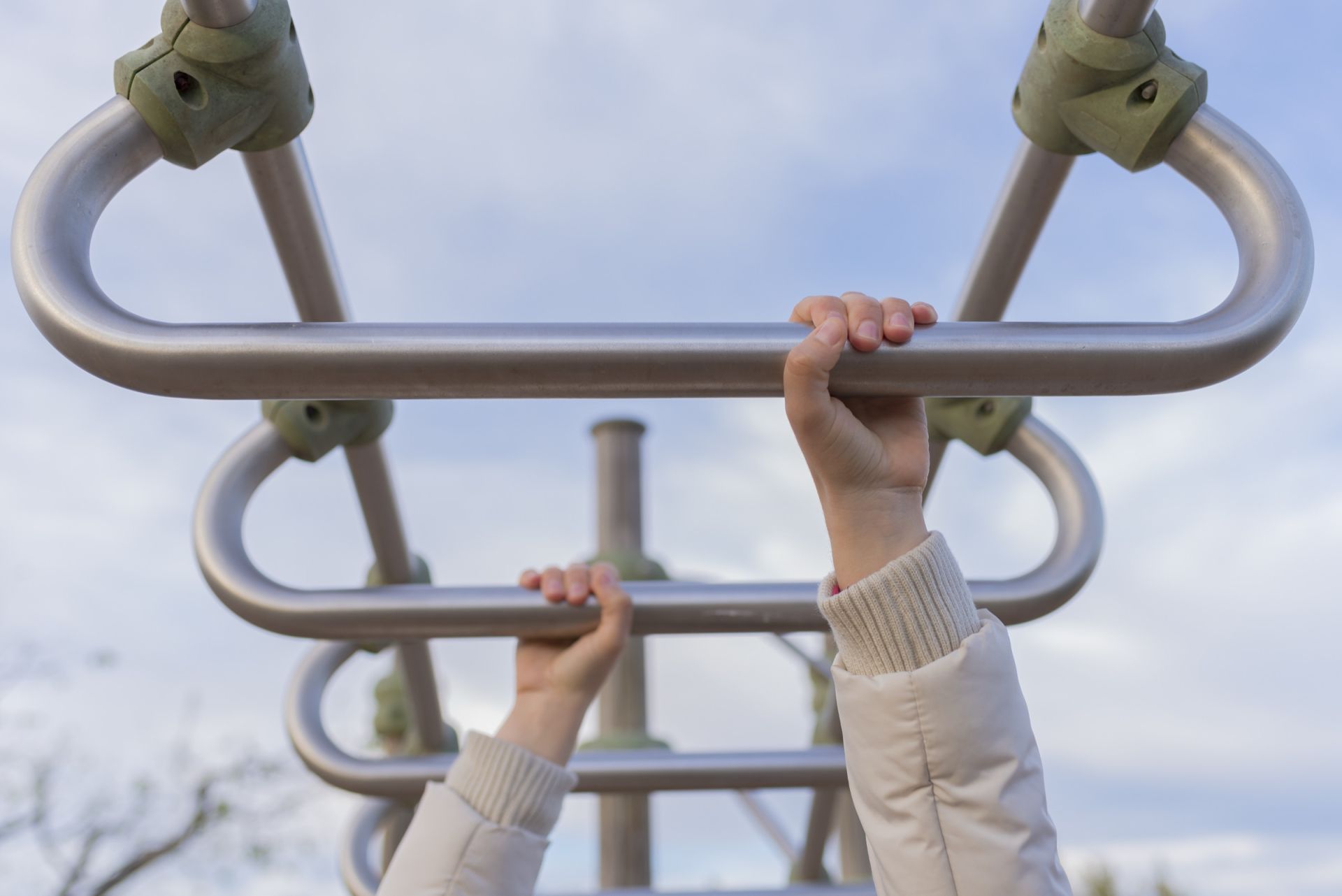 Handen aan een klimrek in een buitenfitness